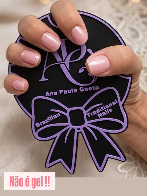 Soft pink manicure by Ana Paula Gaeta, holding an APG branded display